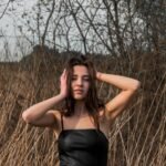 woman in black spaghetti strap top standing on brown grass field during daytime